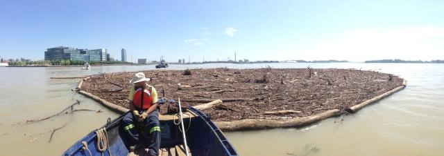 Man in boat towing a large amount of rubbish in a net