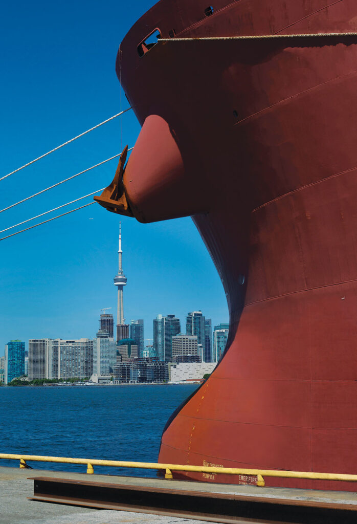 Rear of cargo ship with city skyline in background