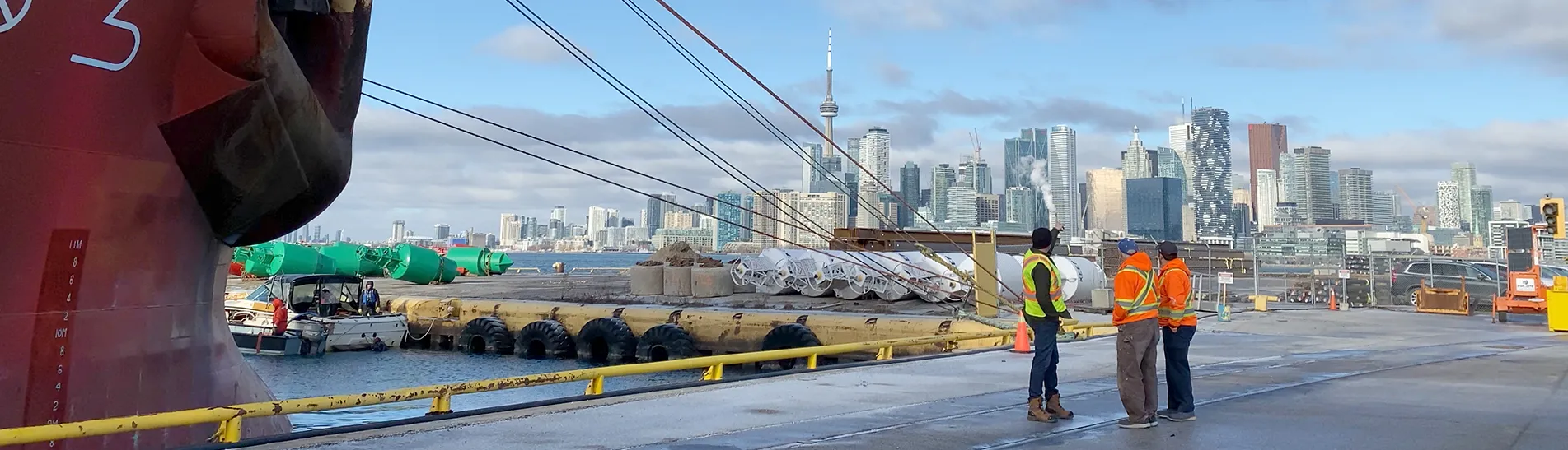 Workers standing at the port with a boat and the skyline in the background